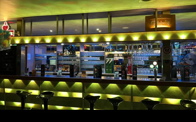 Beleuchtete Bar im Champs mit Zapfanlage und Getränkeregal